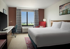 Habitación de hotel con una cama grande, un escritorio, una silla y un televisor.