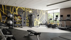 A gym with various exercise equipment, including a bench, dumbbells, and cardio machines. - Hilton Garden Inn Merced (Merced)