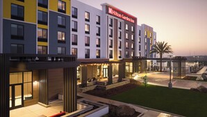A multi-story hotel with a prominent Hilton Garden Inn sign, outdoor seating areas, and a well-lit entrance. - Hilton Garden Inn Merced (Merced)