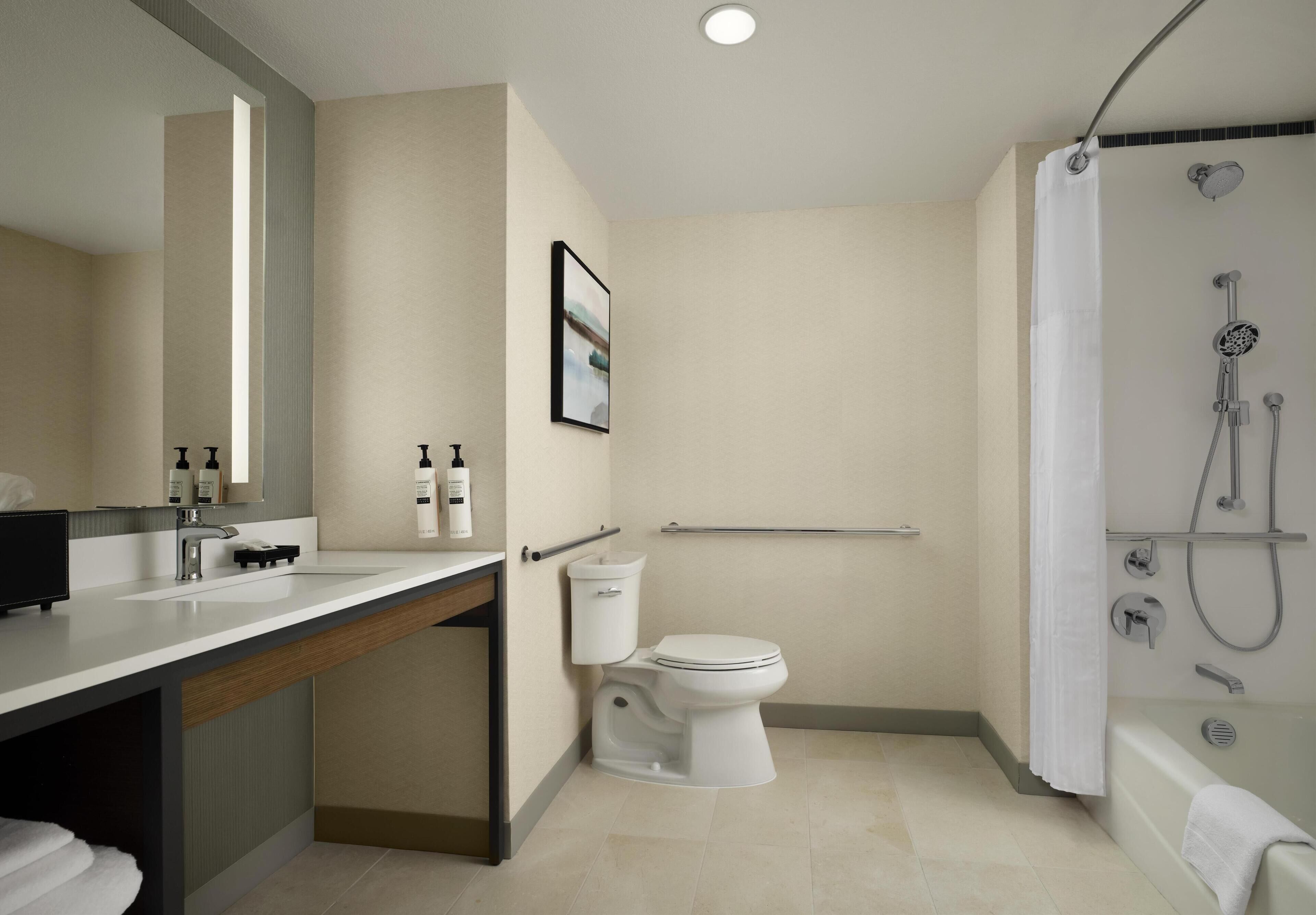 A modern bathroom with a toilet, sink, shower, and a towel rack.