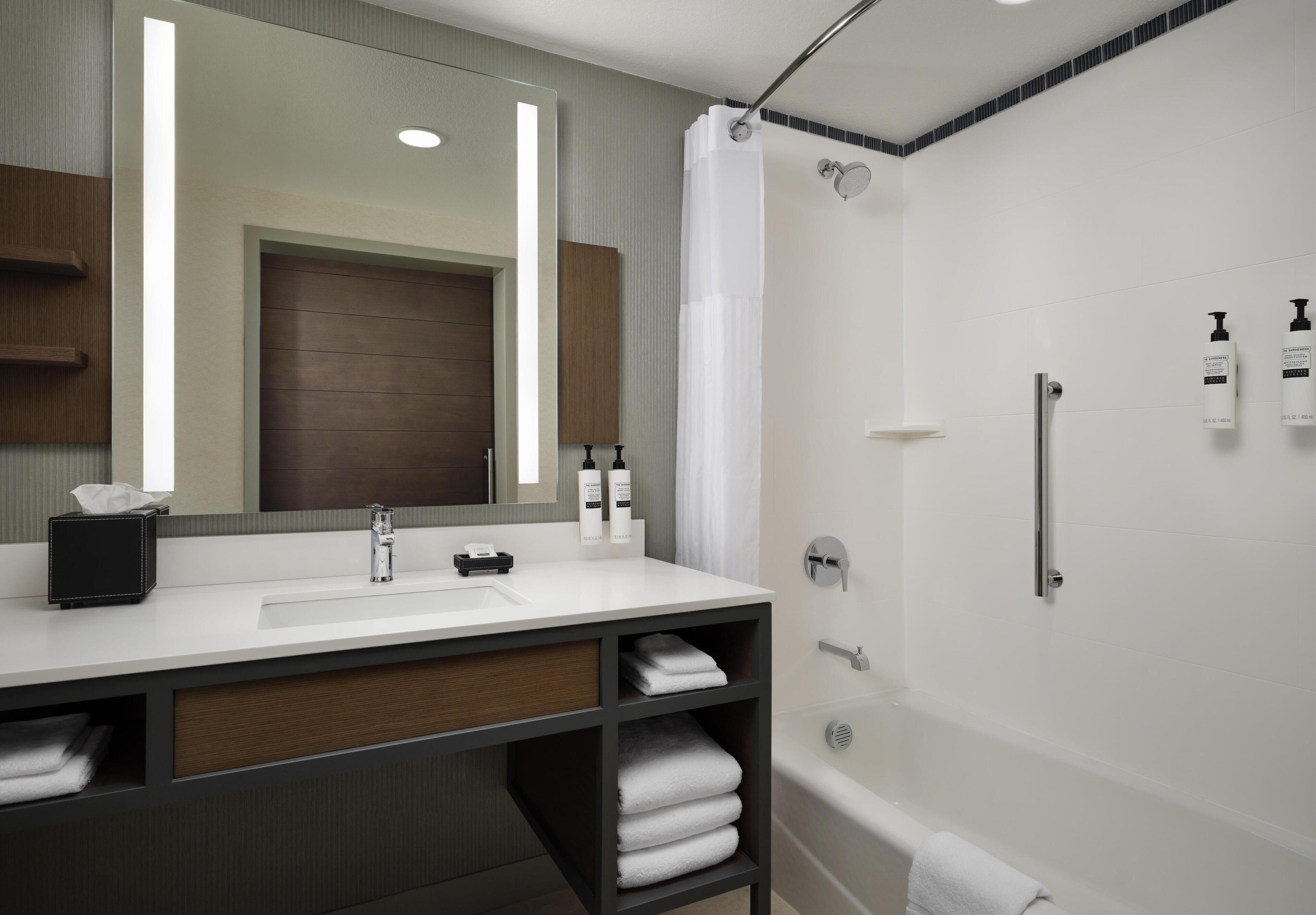 A modern bathroom with a white sink, mirror, and shower.