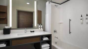 A modern bathroom with a white sink, mirror, and shower.