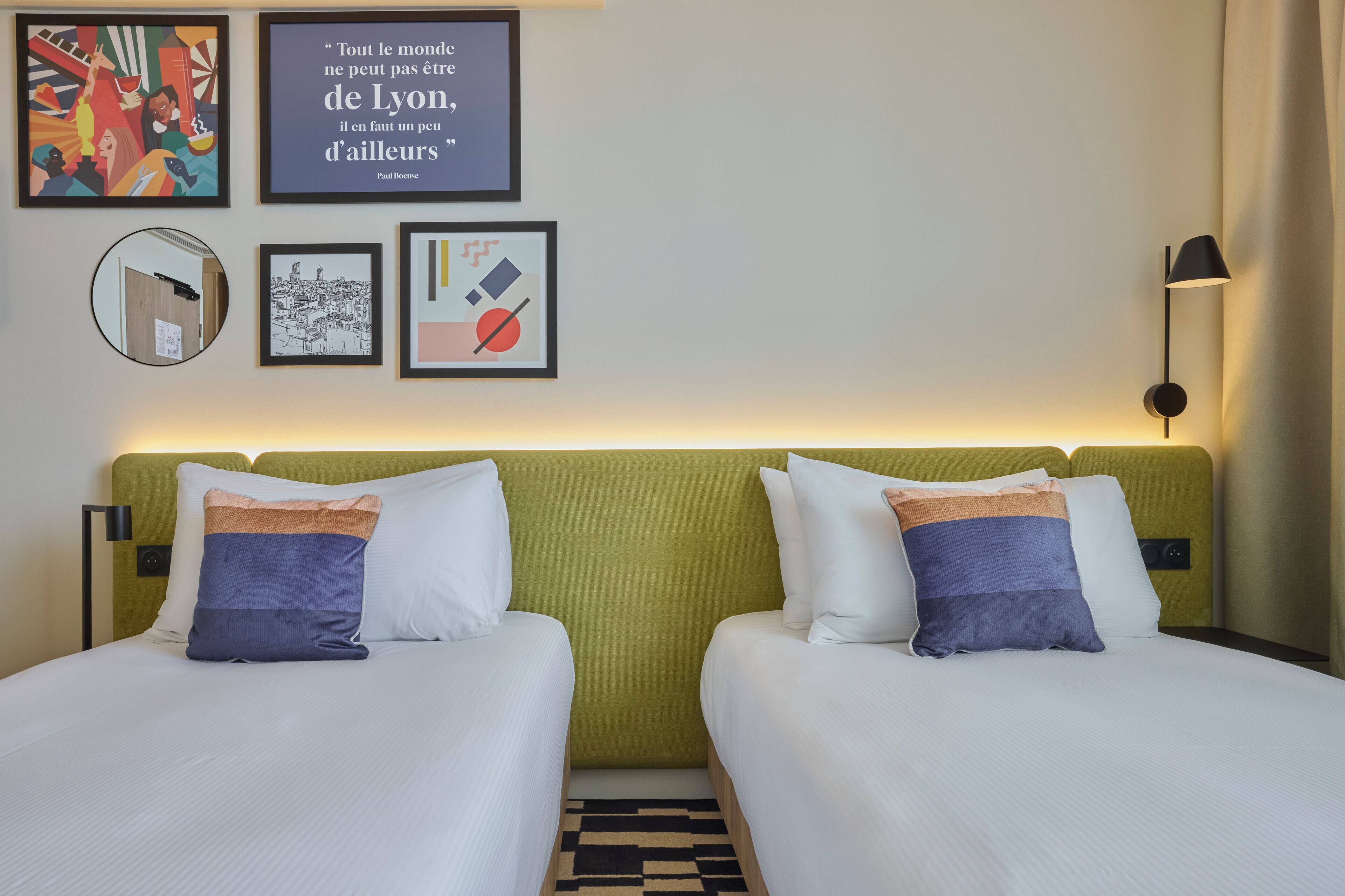 Ein Hotelzimmer mit zwei Betten, einem grünen Kopfteil und einem Kunstwerk an der Wand.