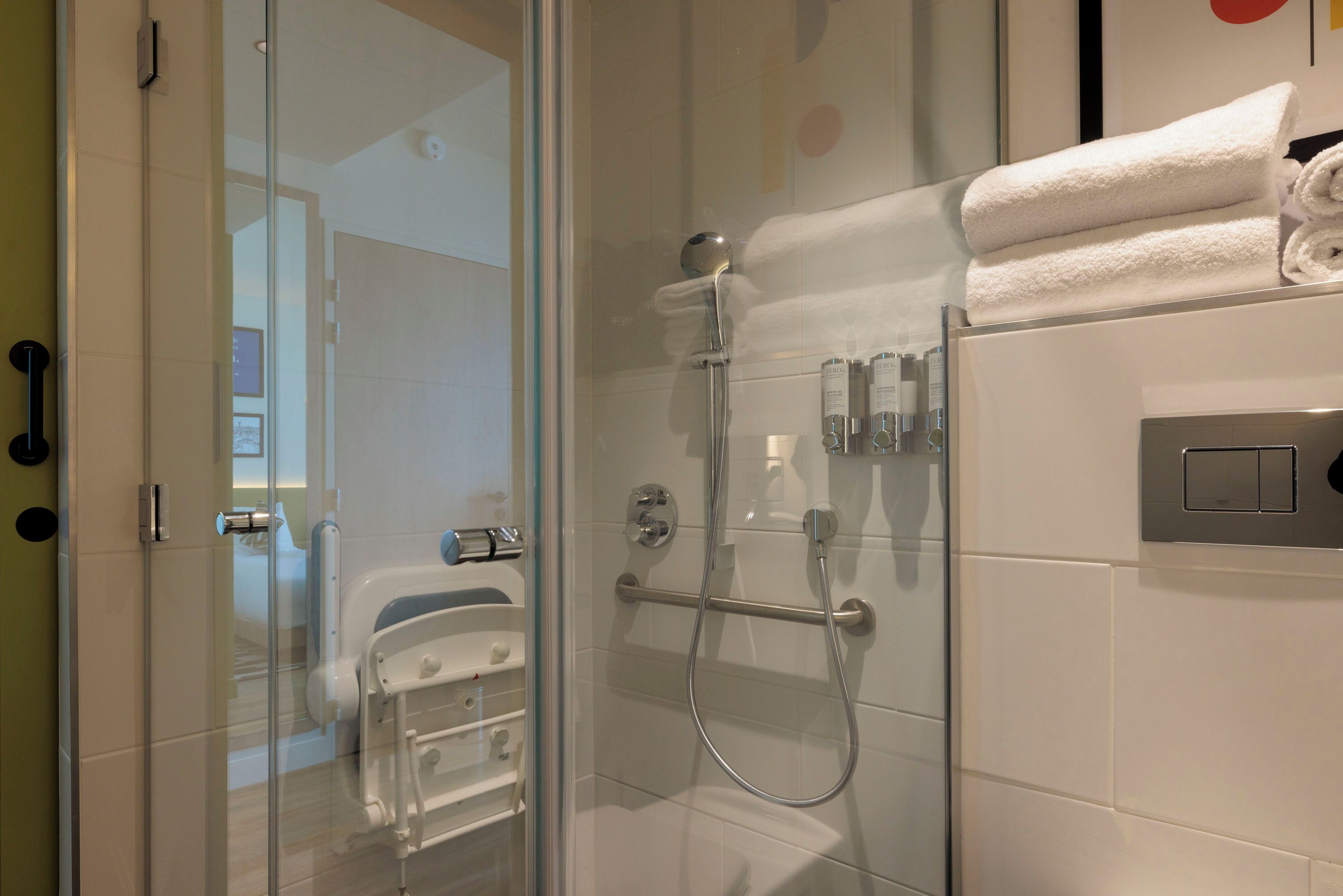 A modern bathroom with a glass shower enclosure, a white bathtub, and a towel rack.