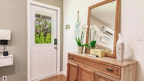A room with a white door, a wooden cabinet with drawers, a mirror, and a small potted plant. - Poolside Paradise/Suite Serenity: in Naples, FL (Naples)