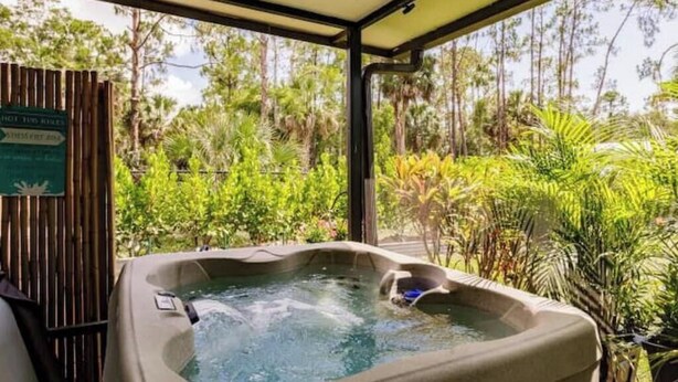 A hot tub in a covered outdoor area with lush greenery in the background. - Poolside/Hibiscus Hideaway:Entire House, Naples FL (Naples)