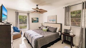 A bedroom with a bed, a ceiling fan, a television, a window with curtains, and artwork on the wall. - Poolside/Hibiscus Hideaway:Entire House, Naples FL (Naples)