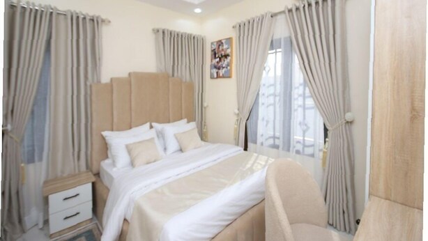 Una habitación de hotel con una cama, una mesita de noche, un aire acondicionado y cortinas.