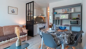 Un espacio habitable compacto con kitchenette, comedor y sofá.