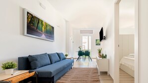 A modern living room with a sofa, a flat-screen TV, a painting, and a dining area with chairs and a table. - Apartment 'Ingrosso Suites - Green' with Private Terrace, Wi-Fi and Air Conditioning (Castri di Lecce)