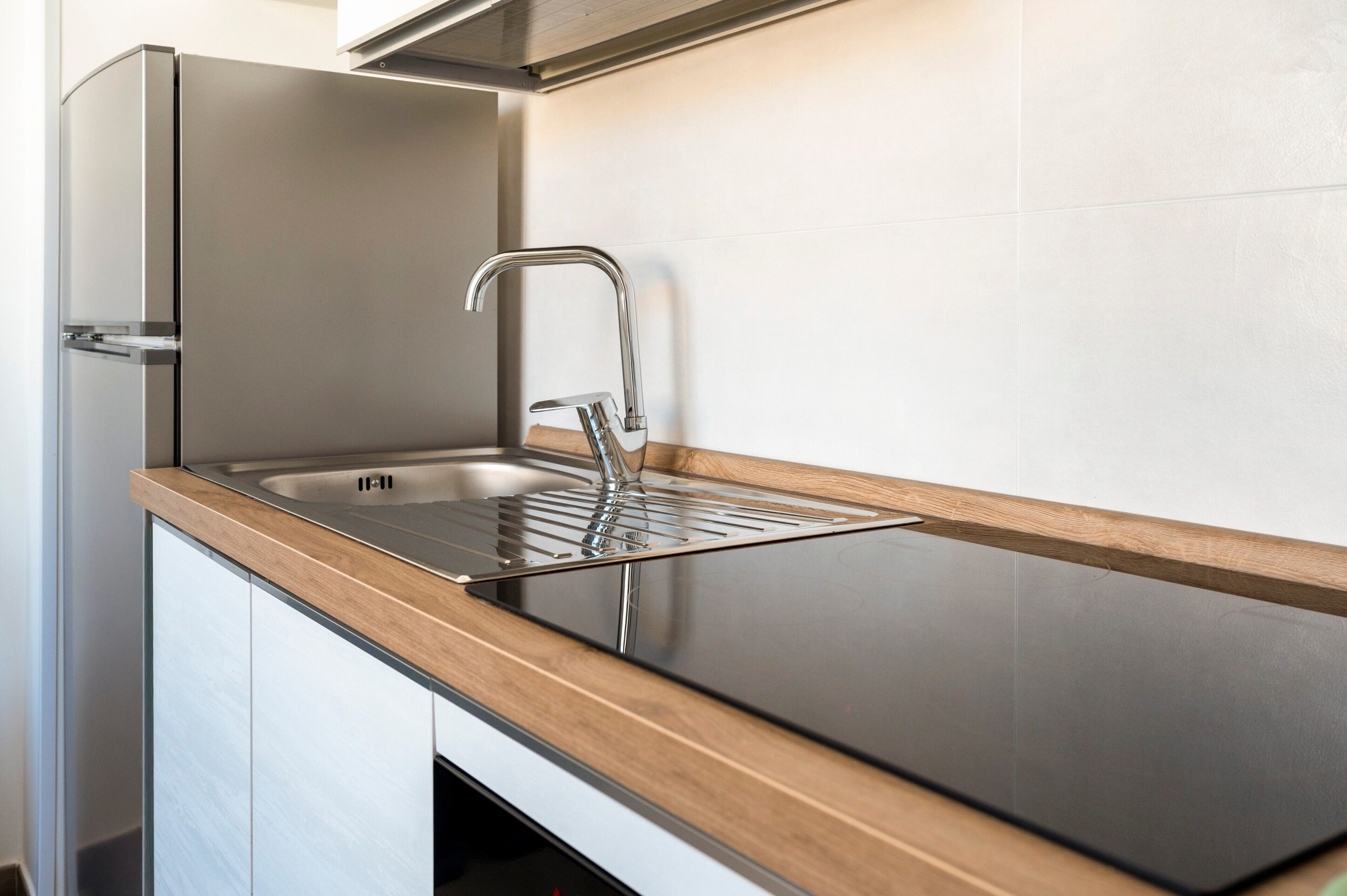 Une cuisine dotée d’un évier en acier inoxydable, d’un plan de travail en bois et d’un robinet moderne.