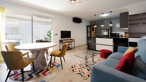 A modern apartment with a dining area, a living room with a sofa, a kitchen, and a balcony with a view.