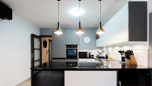 A modern kitchen with black countertops, white cabinets, and pendant lighting.