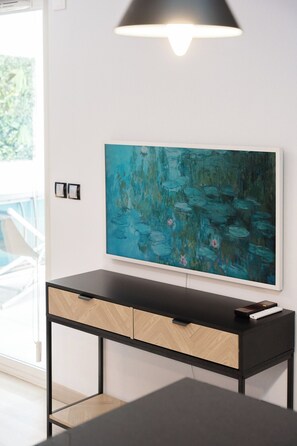 Una habitación moderna con un escritorio negro, un cuadro de un paisaje azul y un ventanal grande.
