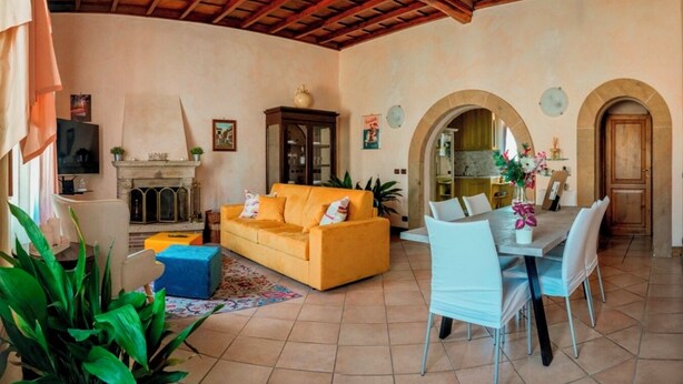 Una sala de estar con sofá, mesa de comedor, sillas y chimenea.