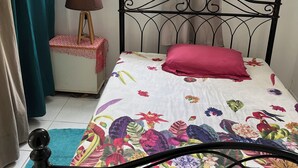 A bedroom with a bed, a nightstand, a lamp, a window, and curtains.