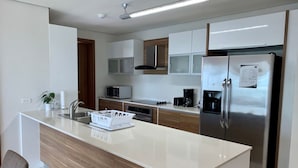 A modern kitchen with a central island, stainless steel appliances, and wooden cabinetry.