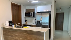 A modern kitchen with a central island, stainless steel appliances, and a wooden cabinet. - Garden Cafe I Spacious 1 Bed Apt With Park View (Panama City)