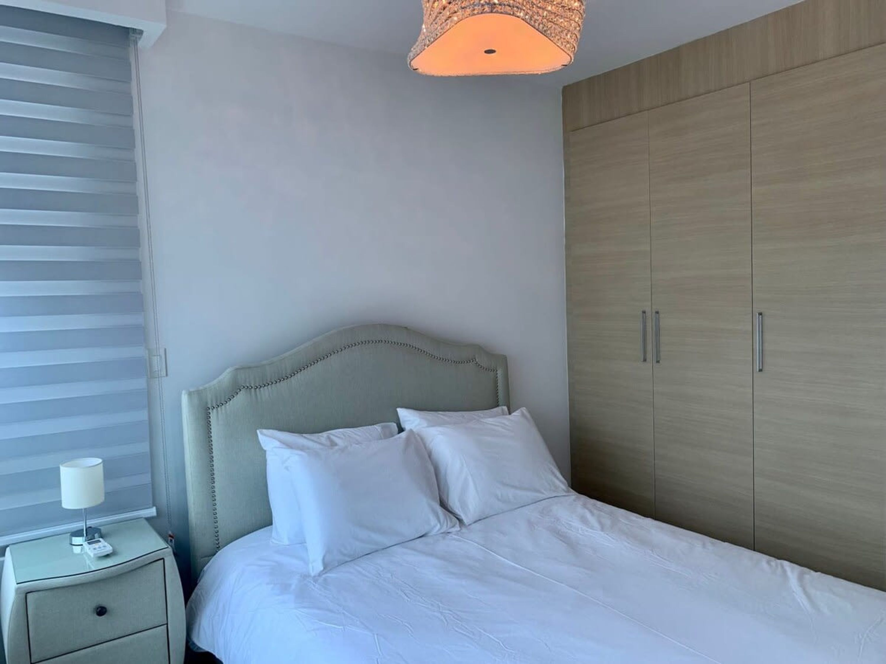 A bedroom with a bed, nightstand, and wardrobe.
