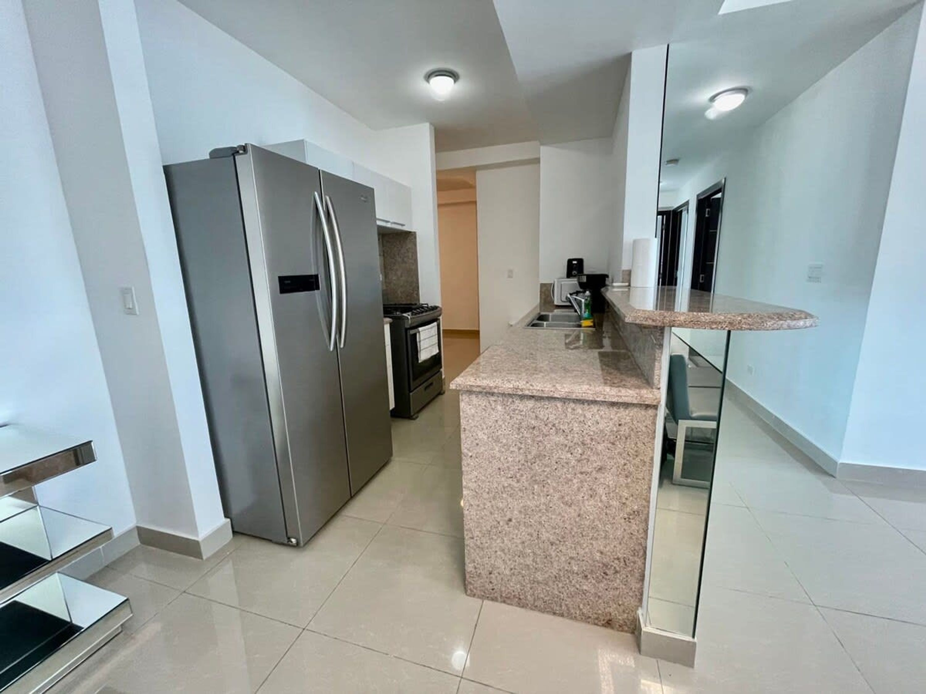 Una cocina moderna con refrigerador de acero inoxidable, encimera de granito y horno empotrado.