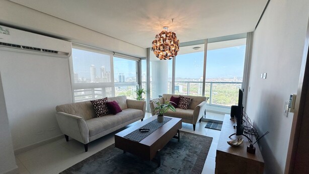 A modern living room with a sofa, armchair, coffee table, and a TV. - Pacific Cafe Classy 1-bedroom in Costa del Este (Panama City)