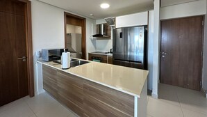 A modern kitchen with a central island, stainless steel appliances, and wooden cabinetry. - Pacific Cafe Classy 1-bedroom in Costa del Este (Panama City)