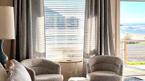 Een hotelkamer met een bed, twee fauteuils, een tafel en een raam met gordijnen.