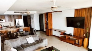 A modern living room with a grey sectional sofa, a coffee table, a TV, and a wooden entertainment unit.