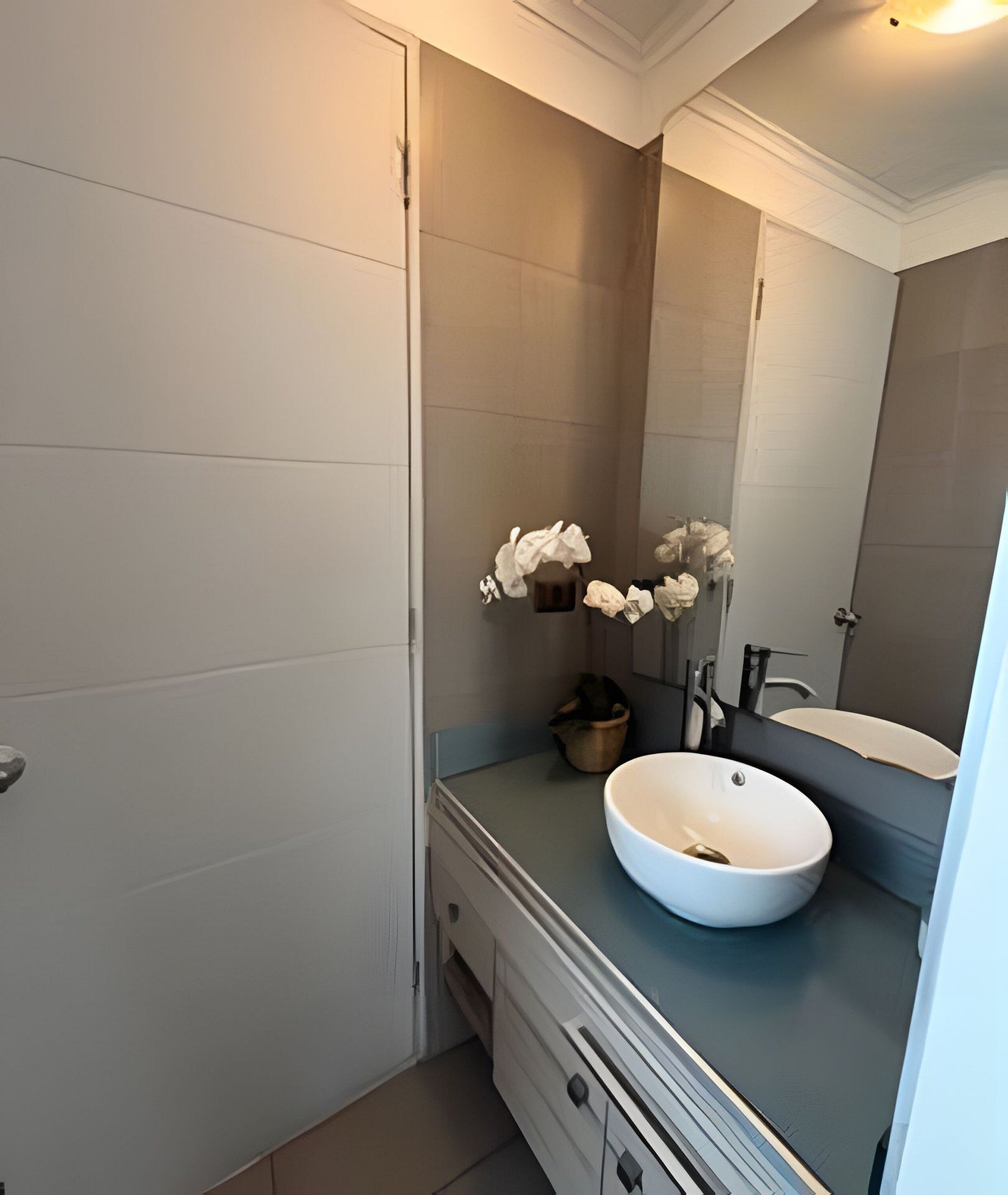 Un bagno moderno con un ampio specchio, un lavandino bianco e un porta asciugamani.