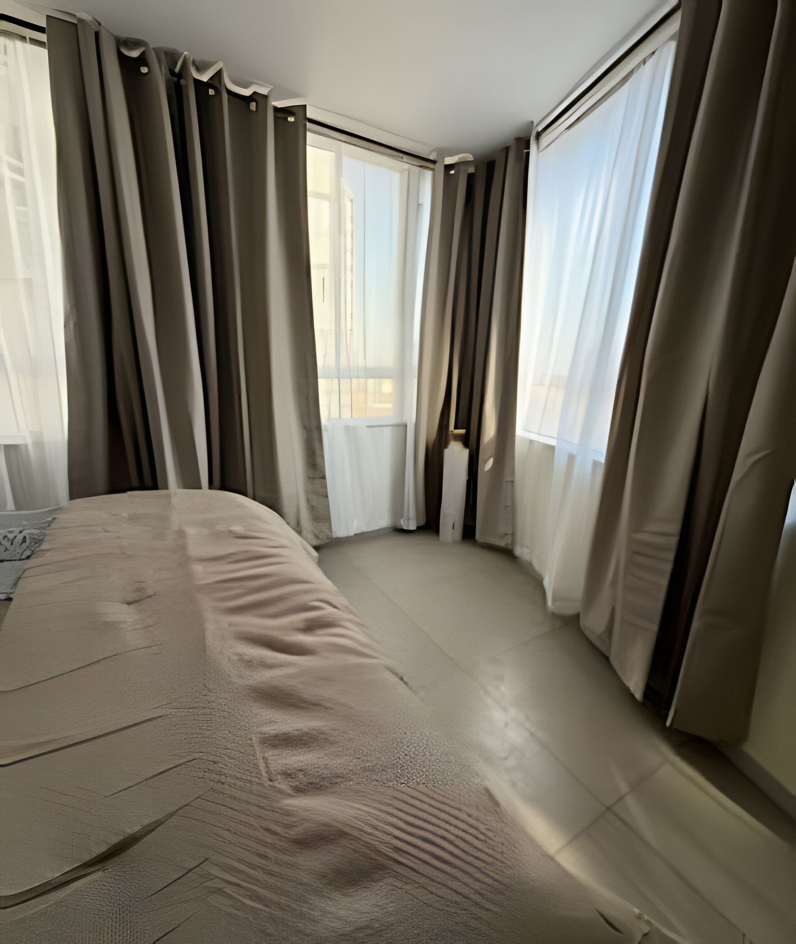 Habitación de hotel con una cama grande, vistas de la ciudad y cortinas translúcidas.