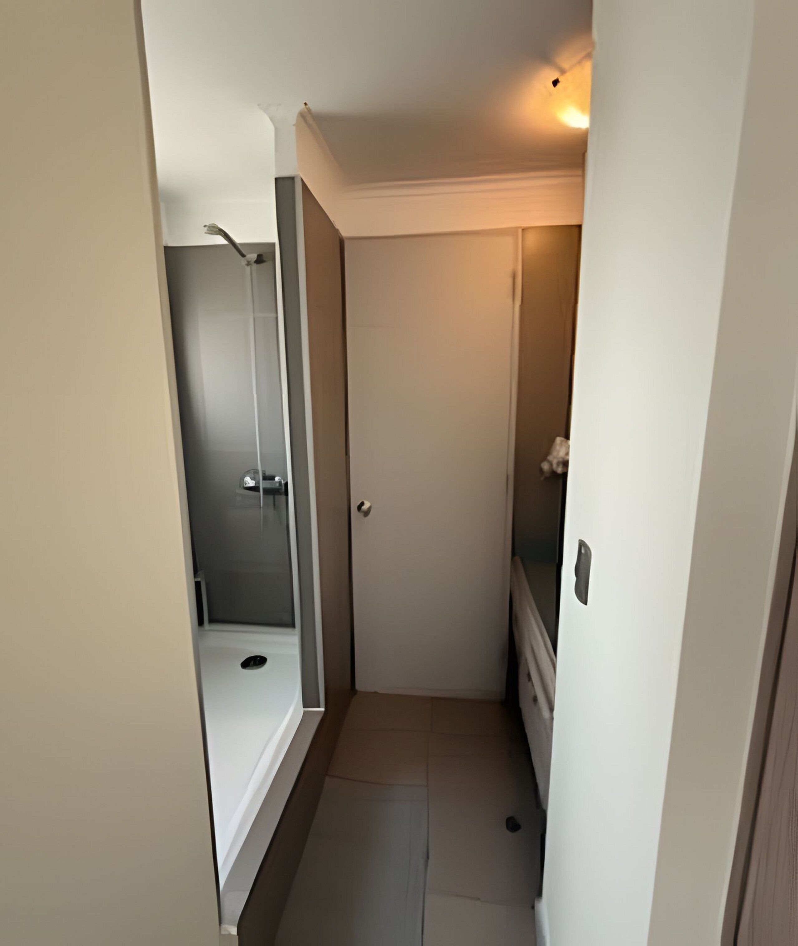Un couloir étroit avec une porte donnant sur une salle de bain.