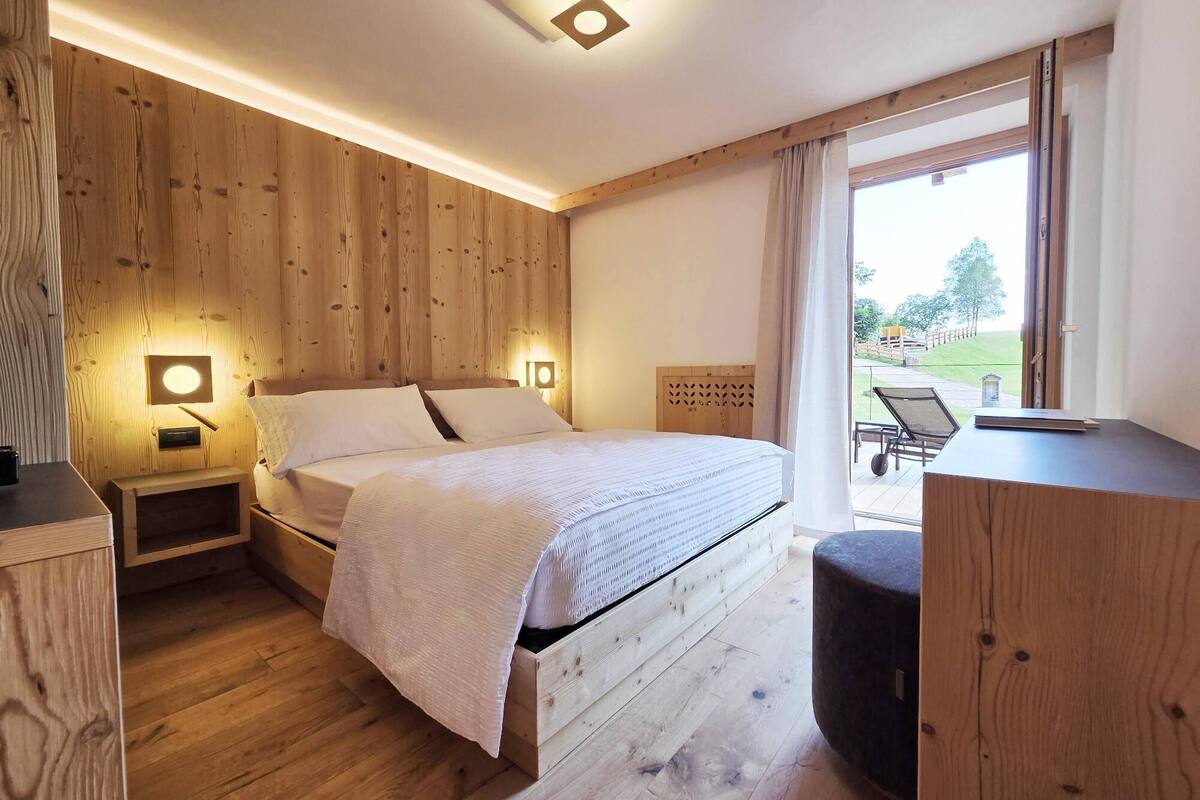 A wooden-paneled bedroom with a bed, bedside tables, and a view of the outdoors.