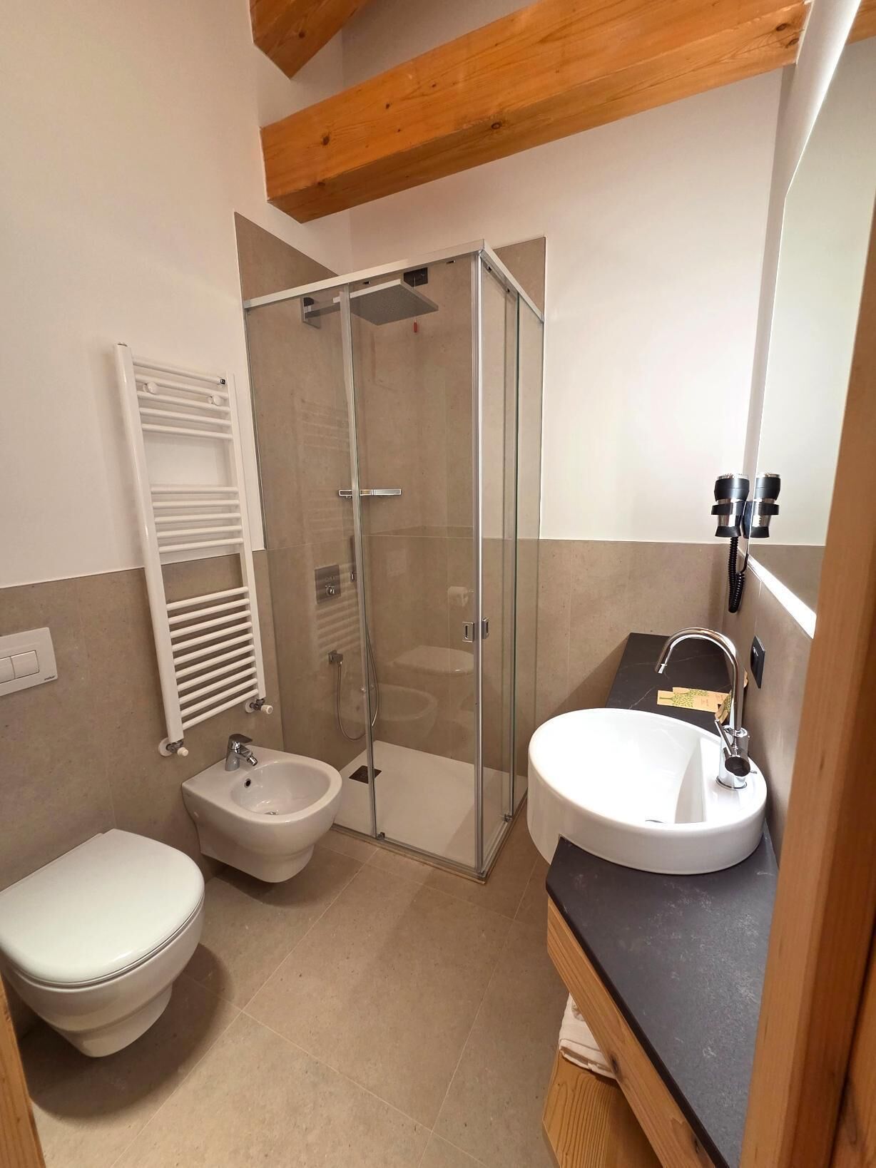 Ein modernes Badezimmer mit einer gläsernen Duschkabine, einem weißen Waschbecken und einem Bidet.