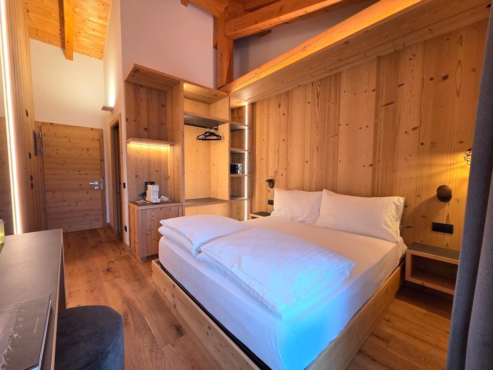 Une chambre dans un chalet en bois, avec un lit, un bureau et une armoire intégrée.