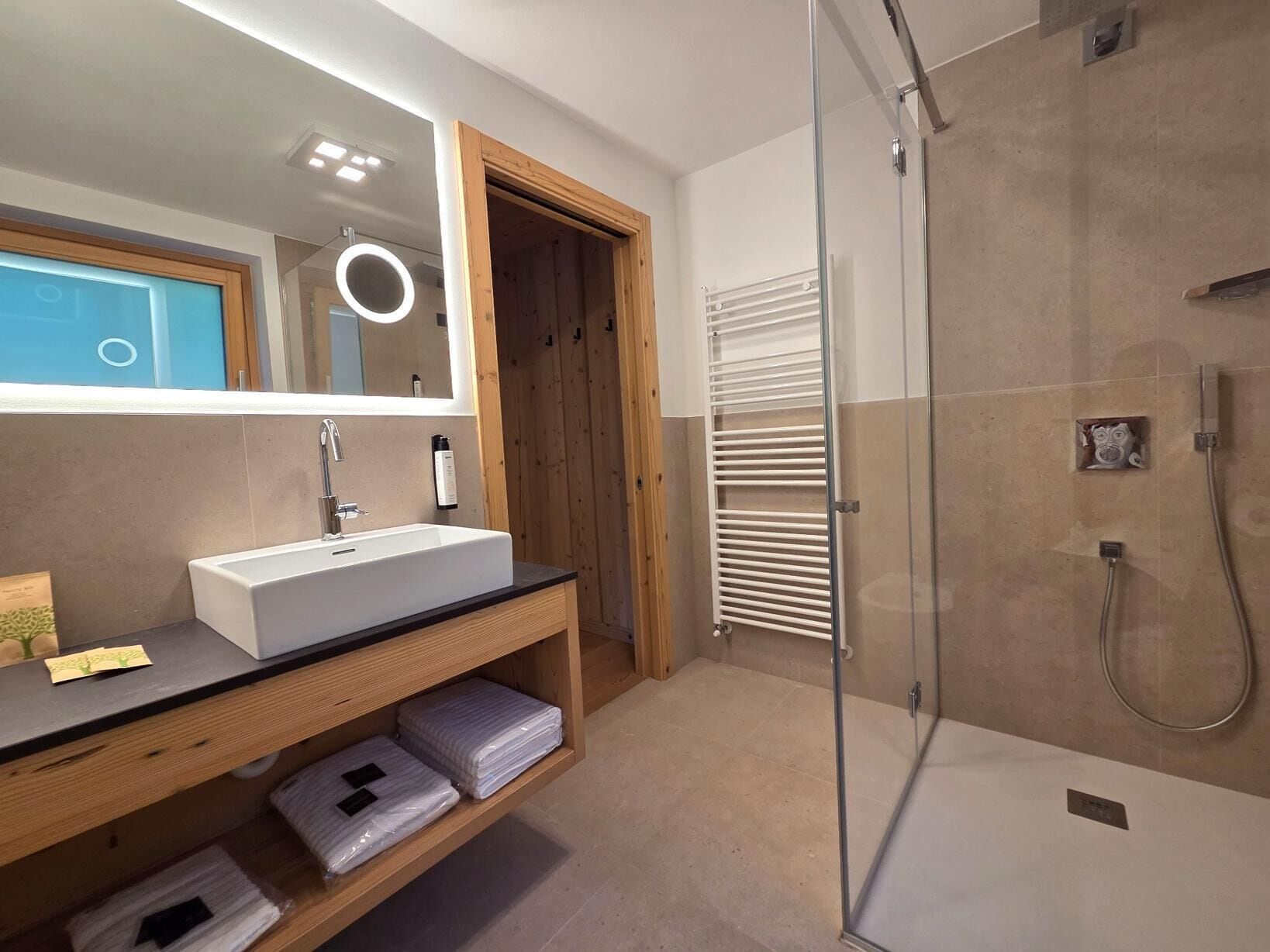 Une salle de bain moderne avec un lavabo blanc, un miroir et une douche en verre.