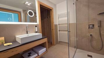Une salle de bain moderne avec un lavabo blanc, un miroir et une douche en verre.
