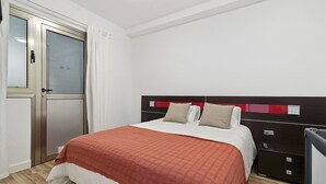 A neatly arranged bedroom with a bed, bedside tables, a wardrobe, and a door with curtains.