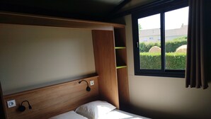 A single bed with a wooden headboard and a window with curtains. - Superb Portland Chalet, 3 bedrooms, sleeps up to 7, all comforts (Évron)