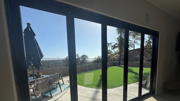 A room with large windows overlooking a backyard with a lawn, patio furniture, and a fence. - Welcome to San Diego’s Poway Paradise, your private oasis on Sycamore Canyon! (Poway)