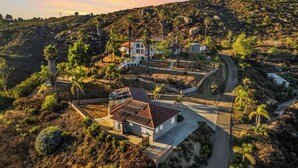 A residential area with a house featuring a sloped roof, solar panels, and a paved driveway. - Welcome to San Diego’s Poway Paradise, your private oasis on Sycamore Canyon! (Poway)