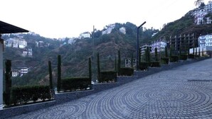 A paved pathway with concentric circles leading uphill, surrounded by greenery and buildings.