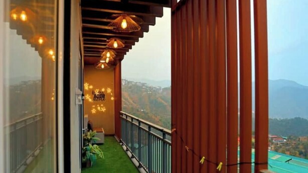 A balcony with a green artificial grass floor, metal railing, and hanging lights.