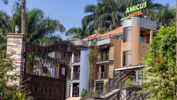 L’extérieur de l’hôtel Amicus se distingue par sa façade à motifs géométriques, son portail imposant et la vue dégagée qu’il offre sur les palmiers environnants.