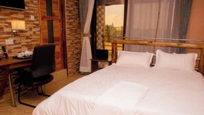 Une chambre d’hôtel avec un grand lit, un bureau avec une chaise, une télévision et une fenêtre avec des rideaux.