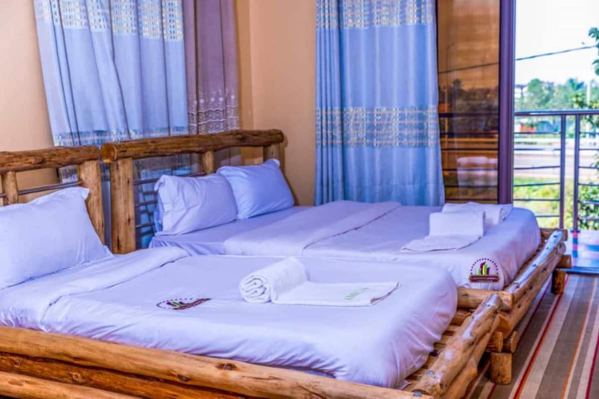 A wooden bed with white linens and towels, a wooden headboard, and a balcony with a railing.