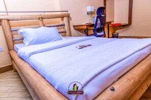 Een hotelkamer met een houten bed, een bureau met stoel en een spiegel.