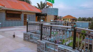 A hotel with a tiled roof, a signboard, and a paved area with a railing.