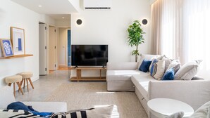 En moderne stue med et fladskærms-tv, en sofa, et sofabord og en plante.