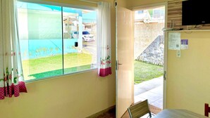 A room with a large window, a television mounted on the wall, and a door leading outside. - Cozy house in Lages, 5 minutes from the pine nut festival. (Lages)