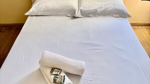 A neatly made bed with white linens and a rolled towel with toiletries. - Cozy house in Lages, 5 minutes from the pine nut festival. (Lages)